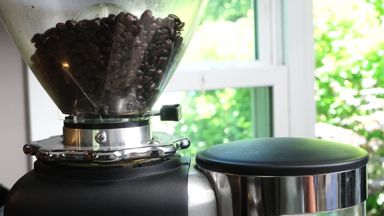 Utilizing a top-tier burr grinder to process freshly roasted coffee beans into a medium consistency. Pulverizing premium coffee beans in a sleek, industrial-grade black Perfect hot cup of hot coffee..