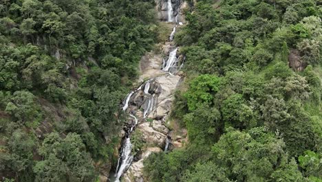 tiro inclinado hacia arriba de una hermosa cascada que fluye hacia abajo en un amplio valle verde, sri lanka