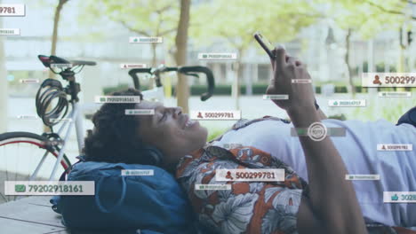 animación de iconos de las redes sociales sobre un hombre afroamericano que usa un teléfono inteligente tendido en un banco en la calle
