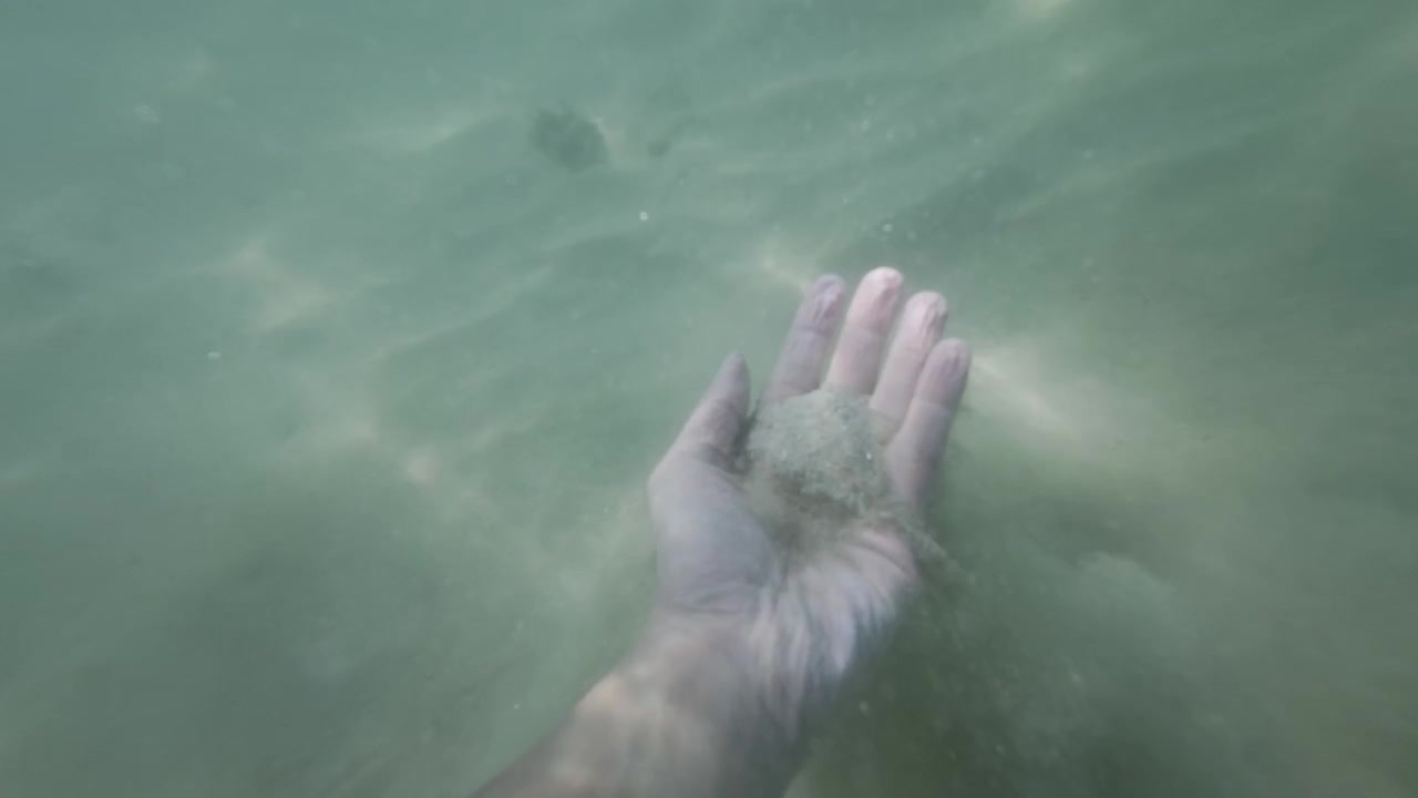 Underwater Selfie POV View of Hand Reaching Down to Touch Sandy Sea Floor in Indonesia