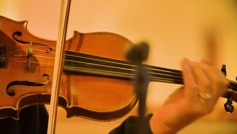 close up of male violinist playing in a string quartet in a small, bright church