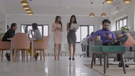 chicas atractivas y felices trabajando e interactuando juntas en un lugar de trabajo corporativo de nueva creación