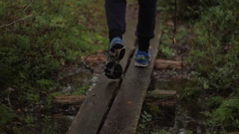 close up on sport shoes with blue color on a small bridge over forest stream dark moody atmosphere autumn