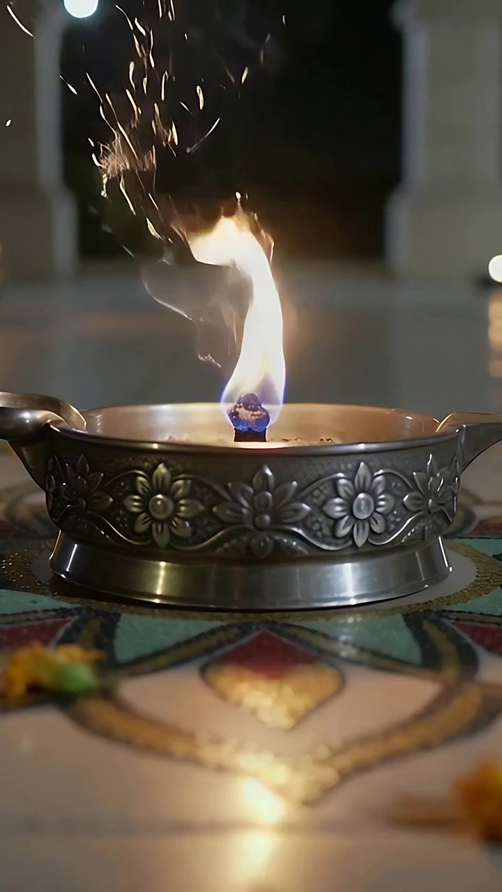 Vertical video: Wick igniting metal diya sparking bicolor flame on rangoli verandah for prayer
