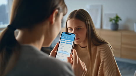 two women discussing financial data on a mobile app