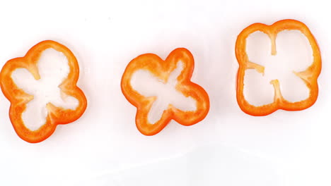 top view: 3 slices of red pepper washed with water on a white background.