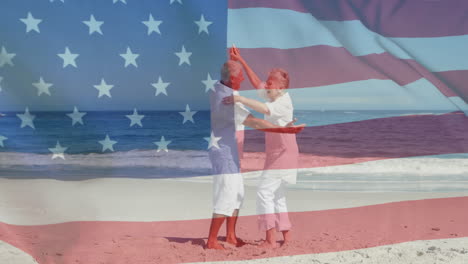 animation of flag of usa over caucasian senior couple dancing on beach in summer