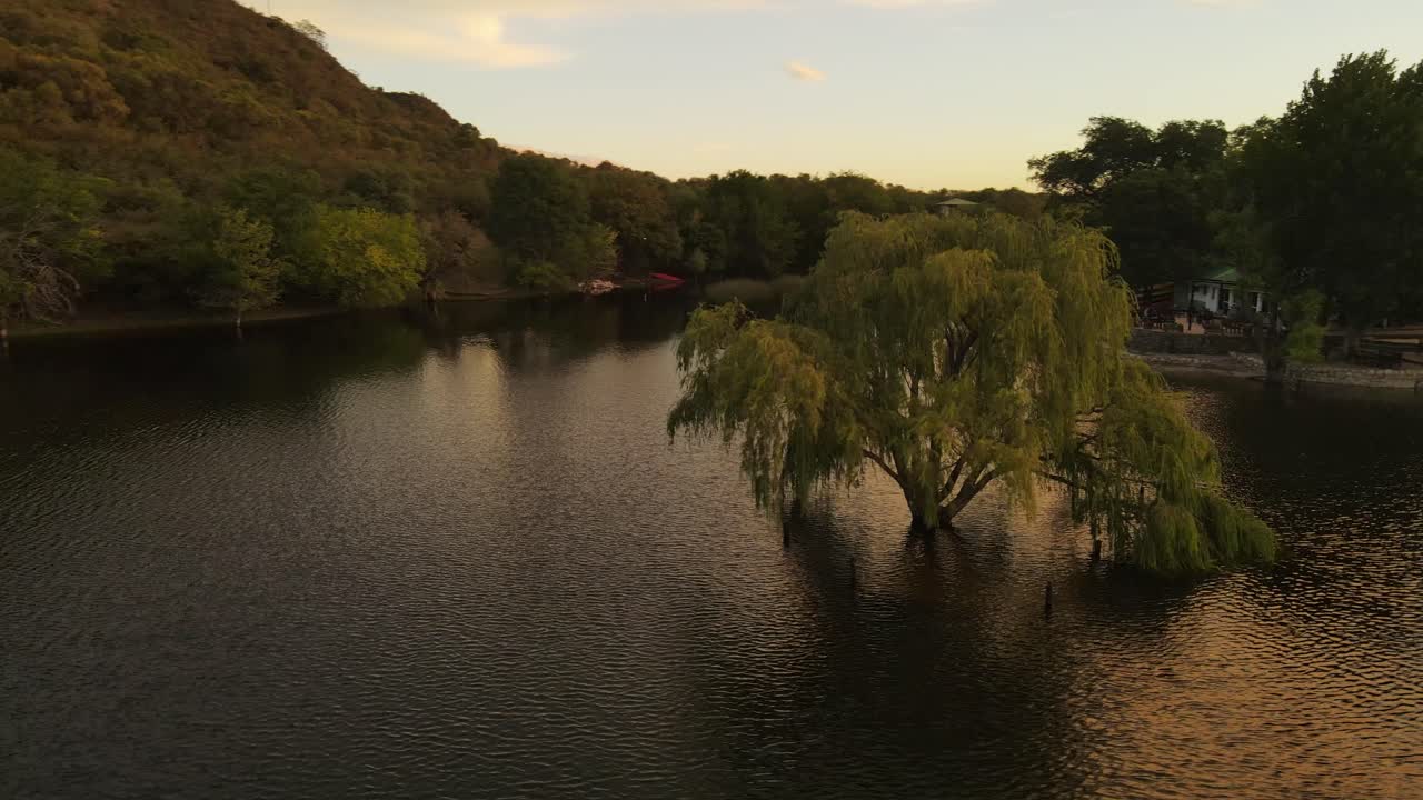 백그라운드에서 일몰과 함께 호수 물에 잠긴 나무 주위를 공전하는 공중 궤도, 아르헨티나의 코르도바