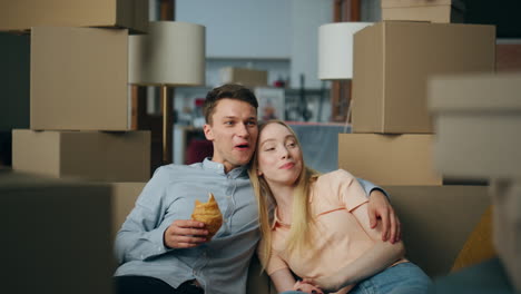 Family-breakfasting-new-home-sitting-at-couch-between-packed-boxes-close-up.