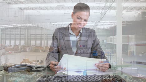 animation of aerial view of warehouse, biracial businesswoman analyzing reports and using computer