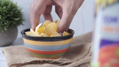 hand picking up chips from a bowl