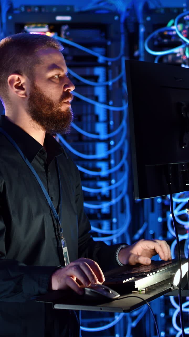 Man programming in a server room. Vertical