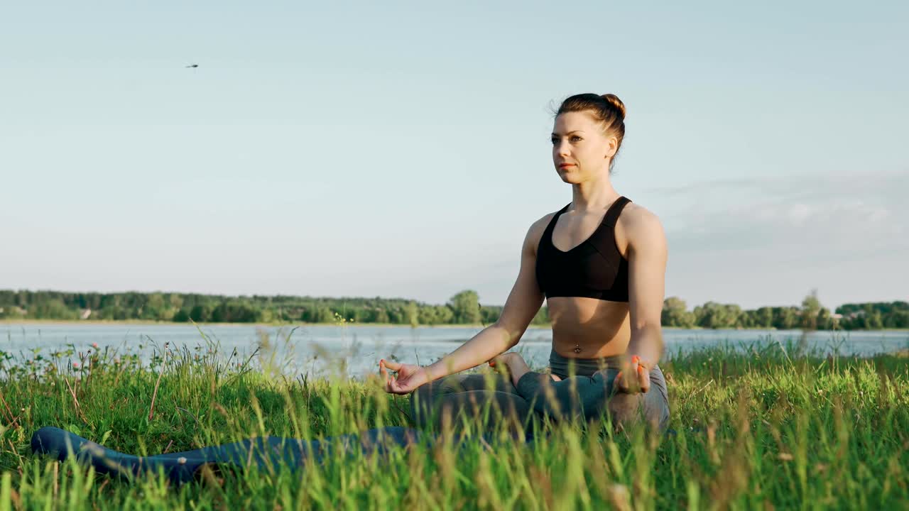 chica bonita en posición de loto al amanecer. mujer haciendo yoga por la mañana en el lago