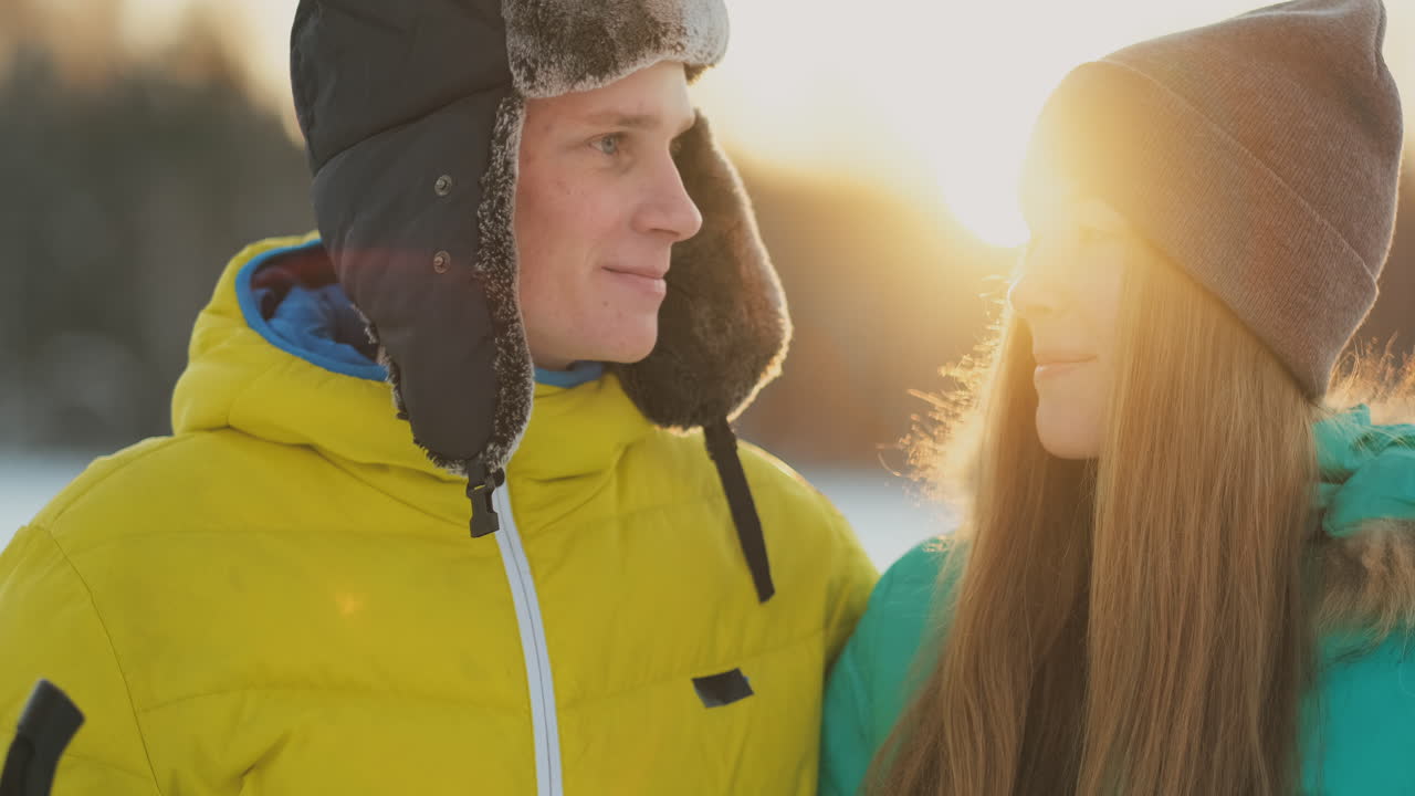In the winter forest at sunset loving couple skiing and look around at the beauty of nature and attractions in slow motion.