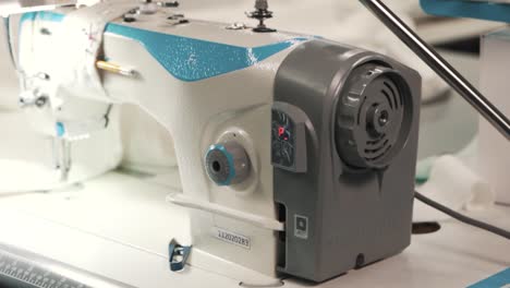 close-up of female hands sewing white fabric on a factory electric sewing machine in a textile production