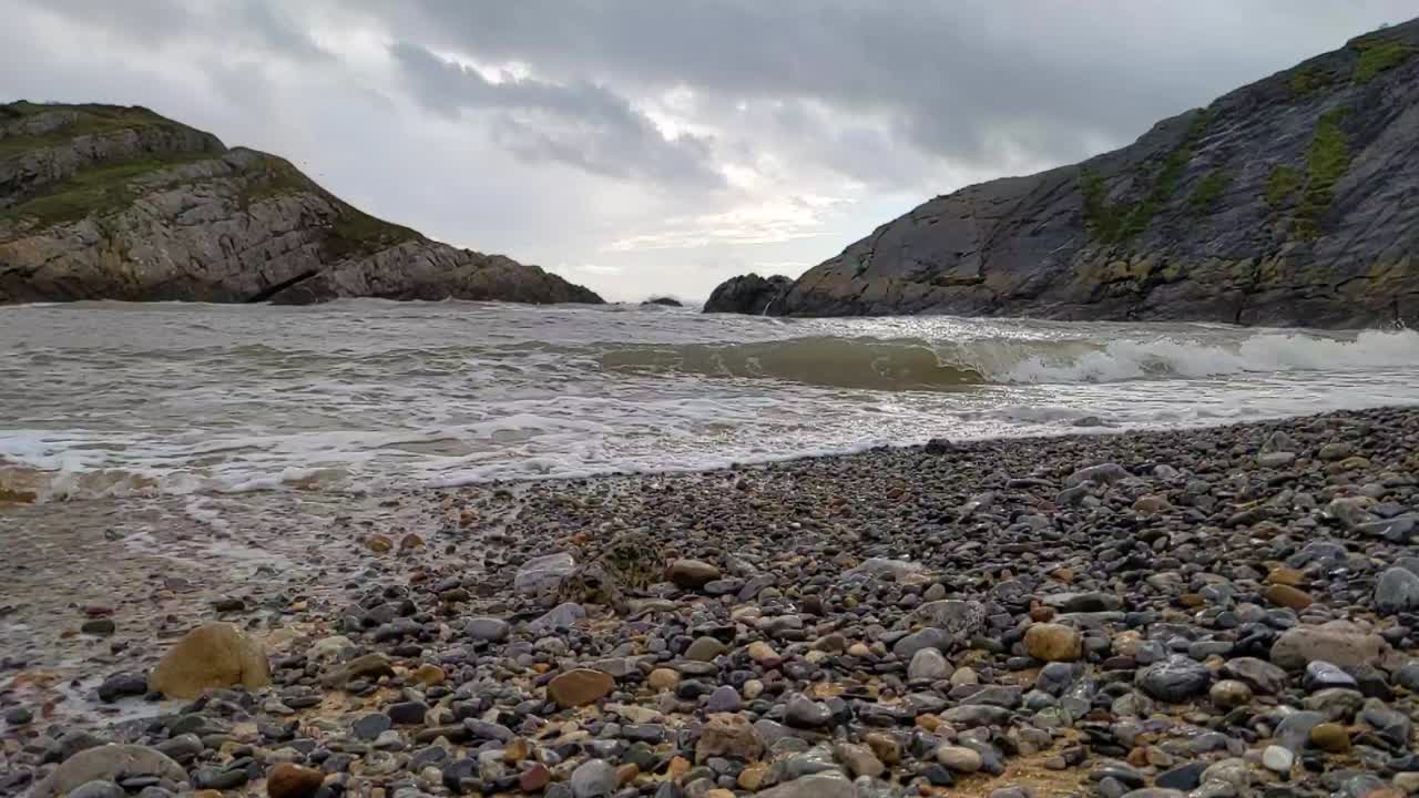 Onde marine al rallentatore che si infrangono su una piccola baia a Mumbles, Regno Unito