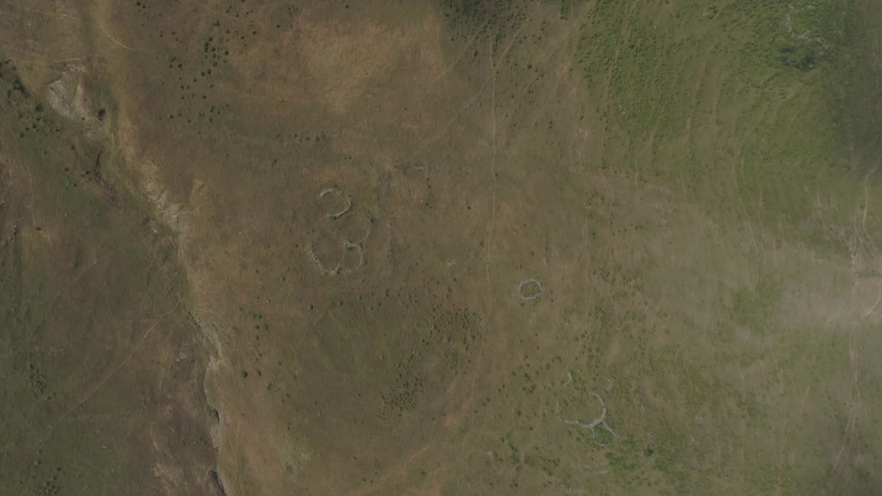 A drone flight flying over a mysterious and barely perceptible man-made structure with circular shapes