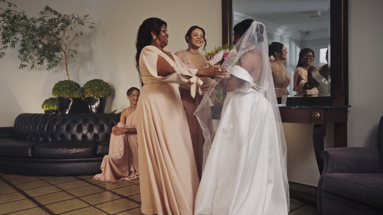 A bride and bridesmaids share emotional hugs and prepare for a wedding