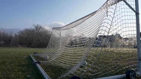 スローモーション: サッカー ボールがサッカー ゴールの氷の網にぶつかり、粉々になった氷が空中に爆発する