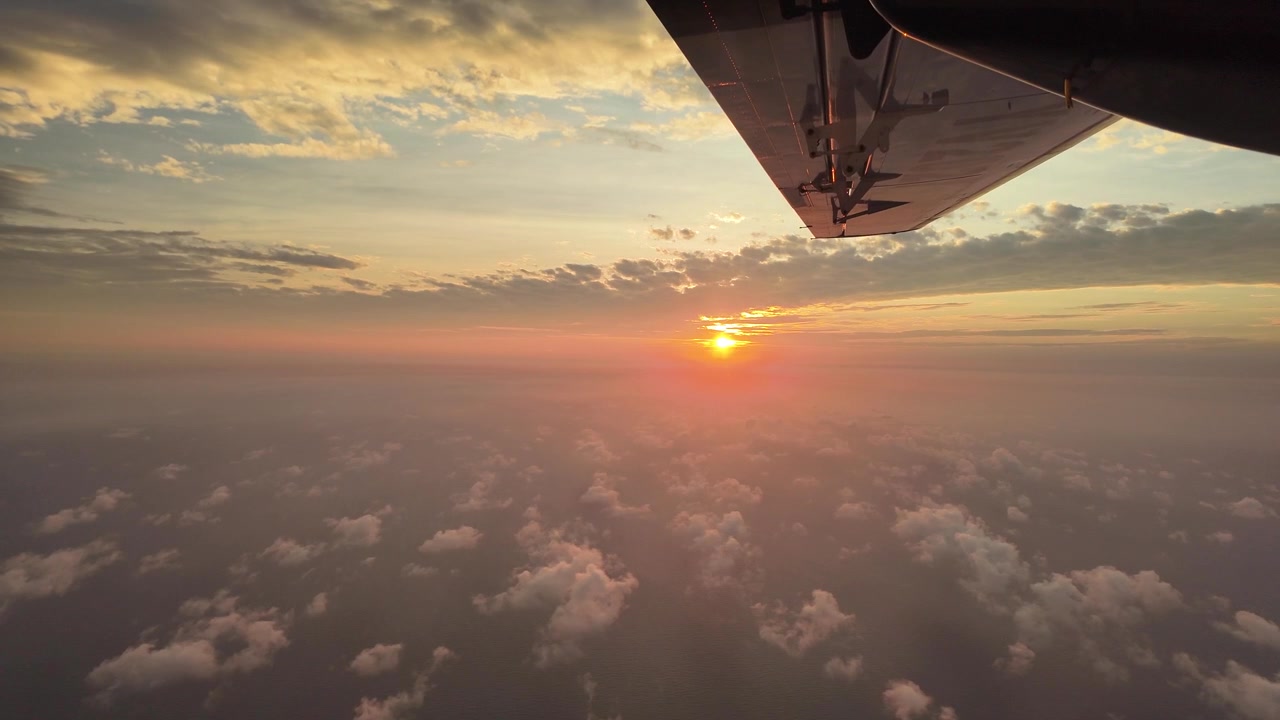 Transizione dalla vista del cielo dorato al tramonto attraverso il finestrino dell'aereo all'interno scuro della cabina, che sfuma nel nero.