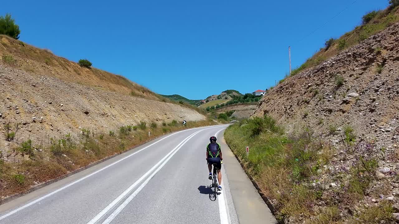 Cykling på landlige bakker gennem smuk landskabsvej i malerisk albansk landsby, sport og passion kombineret.
