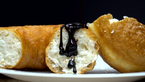 a piece of delicious sweet donut pouring by hot melted cocoa. close up