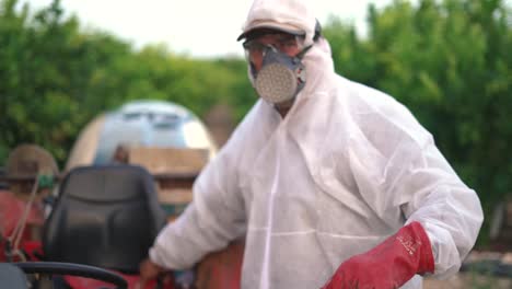 agricultor usando luvas de proteção enquanto pulveriza pesticidas em árvores de limão com um trator