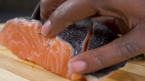 a close up side view shot of raw fish being sliced on a chopping board in slow motion