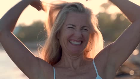 mooie vrouw met tegenlicht die naar de lucht kijkt, haar armen uitsteekt en er zorgeloos uitziet terwijl ze op een tropisch strand is