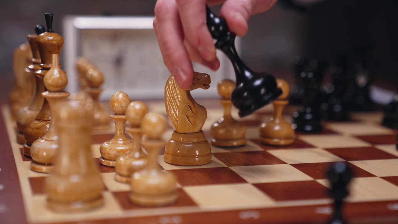 Primo piano di mano che cattura pezzo di scacchi su scacchiera
