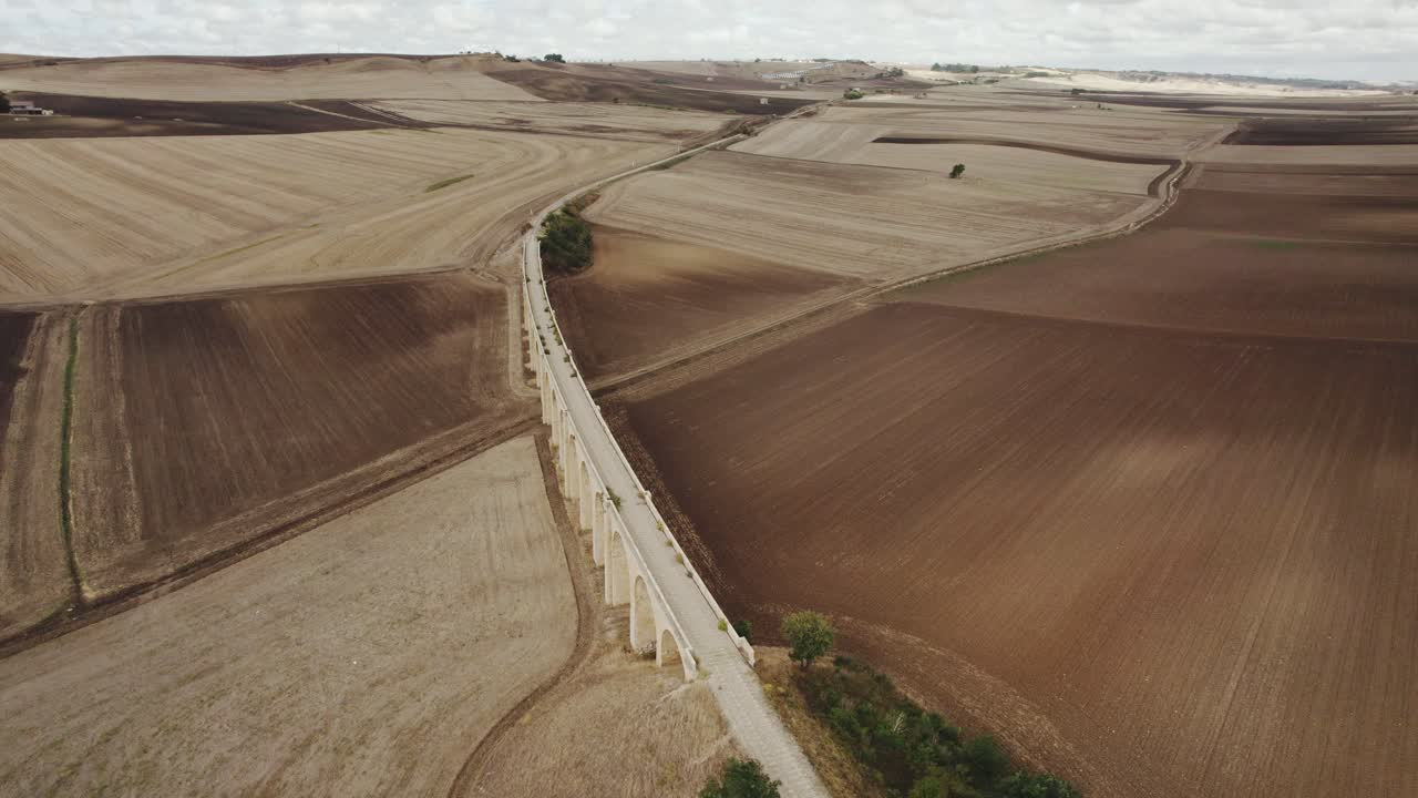 drone volando en movimiento circular alrededor de un viejo puente con vías de tren entre campos de cultivo en italia en 4k