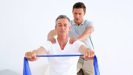 physiotherapist watching patient stretching blue resistance band