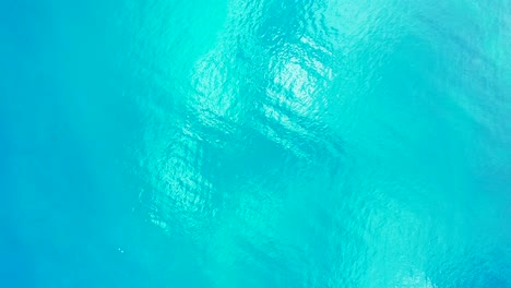 glassy sea texture with turquoise water reflecting sunlight, copy space with abstract patterns on tropical seascape, indonesia