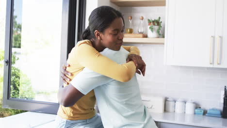 Una-Pareja-Afroamericana-Comparte-Un-Cálido-Abrazo,-Abrazándose-En-La-Cocina.