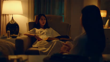 two women talking in a living room at night