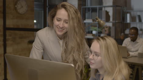 two female employees looking something at computer and talking together in the office 3