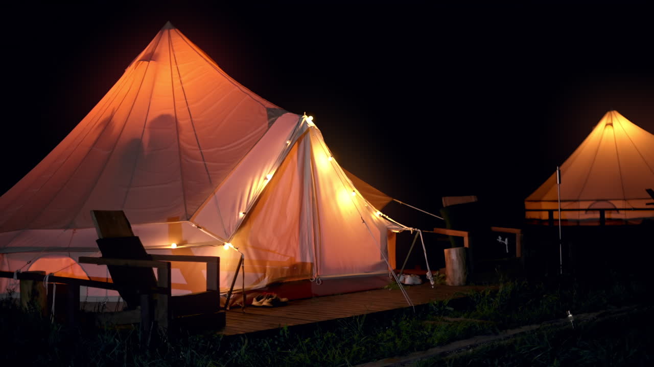 Couple dancing inside a tent with nightlights. Glamping at night. Slow motion