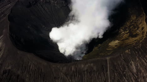 Aerial-view-tilting-away-from-smoking-mount-Bromo-caldera,-in-Java,-Indonesia