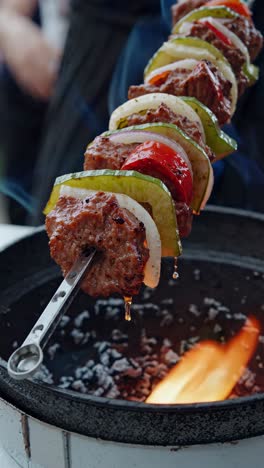 close-up, low-angle shot of juicy kebabs on a skewer over a flame, capturing the sizzle and vibrant