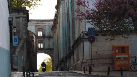 Home-delivery-bike-with-a-medieval-bridge-in-the-background,-near-Graça-in-Lisbon,-Portugal