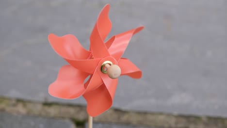 single orange coloured pinwheel spinning very fast against grey patio slabs