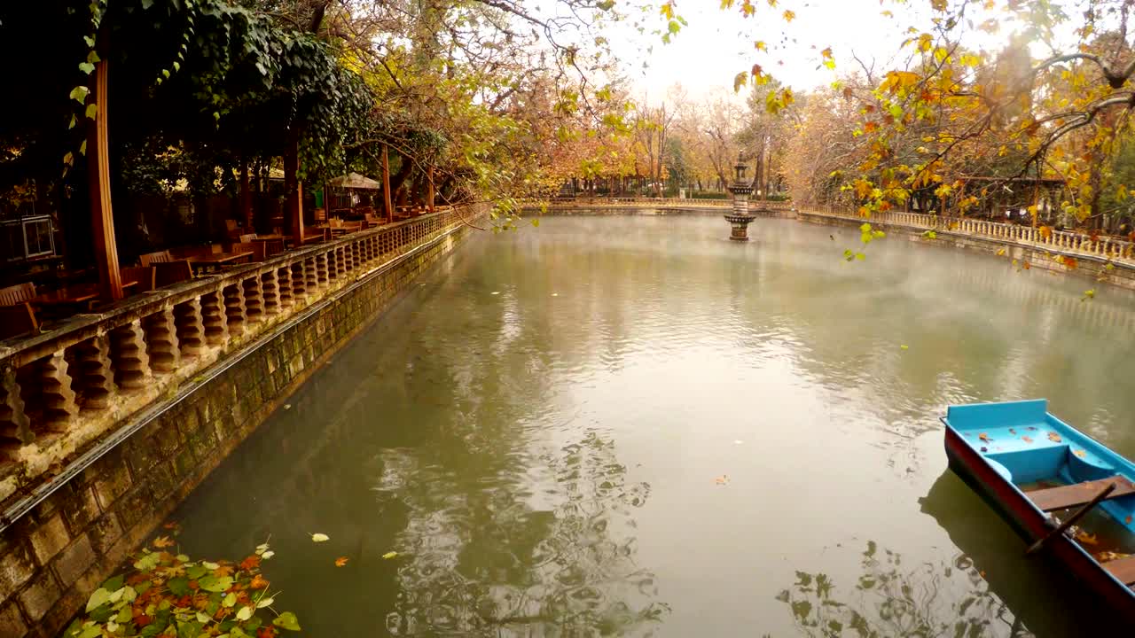 아인-젤리 호수 에서 안개가 떠다니며 푸른 보트가 레스토랑 근처에 녹색과 노란색 나무 주변에 우르파 공원