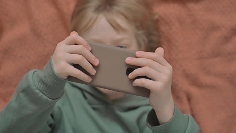 retrato de niño pequeño con un teléfono inteligente viendo un video en línea