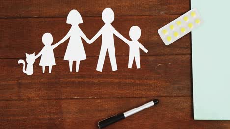 Close-up-of-a-paper-cut-out-of-a-family-with-tablet-and-pen