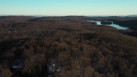 giro de drones que revela una vista de colinas boscosas y lagos de montaña y casas rurales de montaña al amanecer de invierno