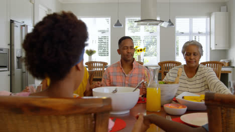 Vista-Frontal-De-Una-Familia-Negra-De-Varias-Generaciones-Orando-Juntos-En-La-Mesa-Del-Comedor-En-Una-Cómoda-Casa-4k
