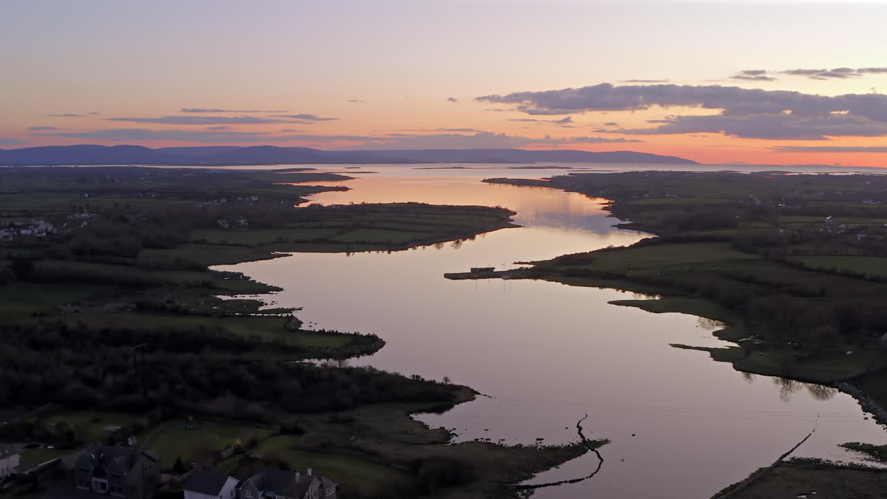 Winding estuary near Clarinbridge bathed in evening sunset with sky reflecting on water, pullback descend