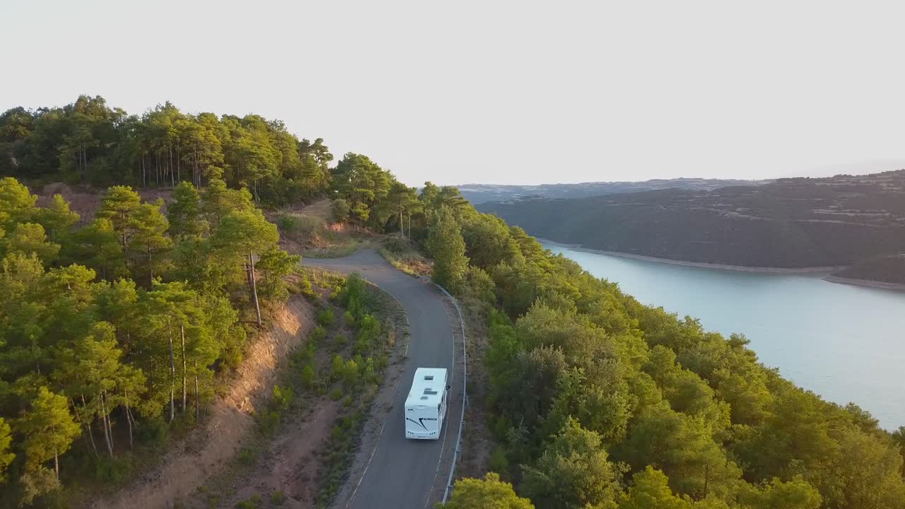 vista aérea de drones de una casa rodante moderna que viaja a lo largo de un camino solitario en un paisaje natural increíble al atardecer