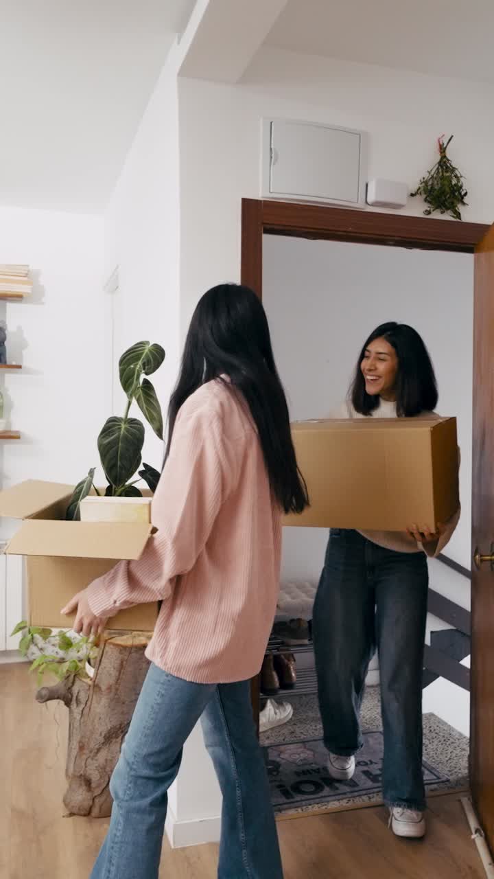 Happy Young Women Moving into New Apartment with Cardboard Boxes