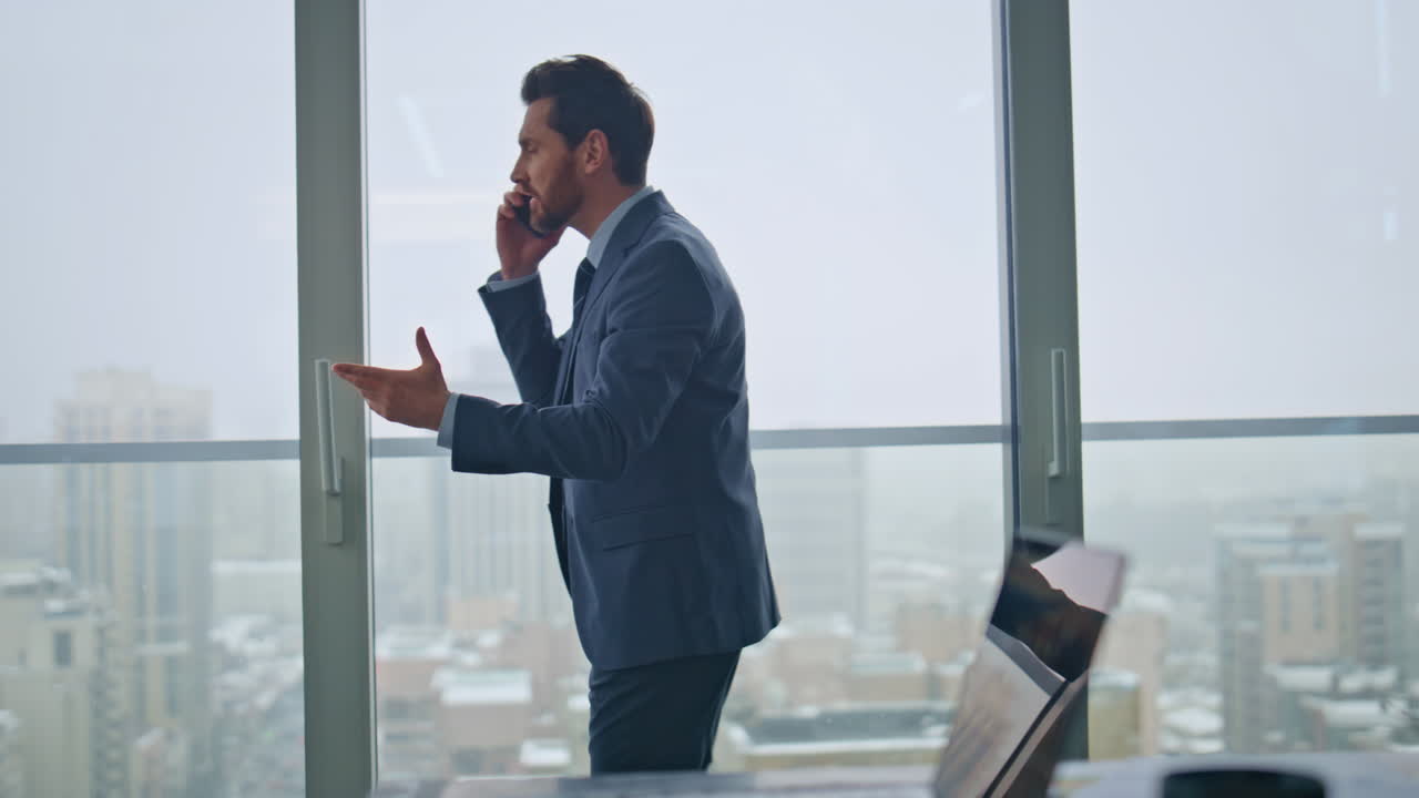 imprenditore arrabbiato chiamata delusa mano gesticolante cityscape ufficio vista posteriore